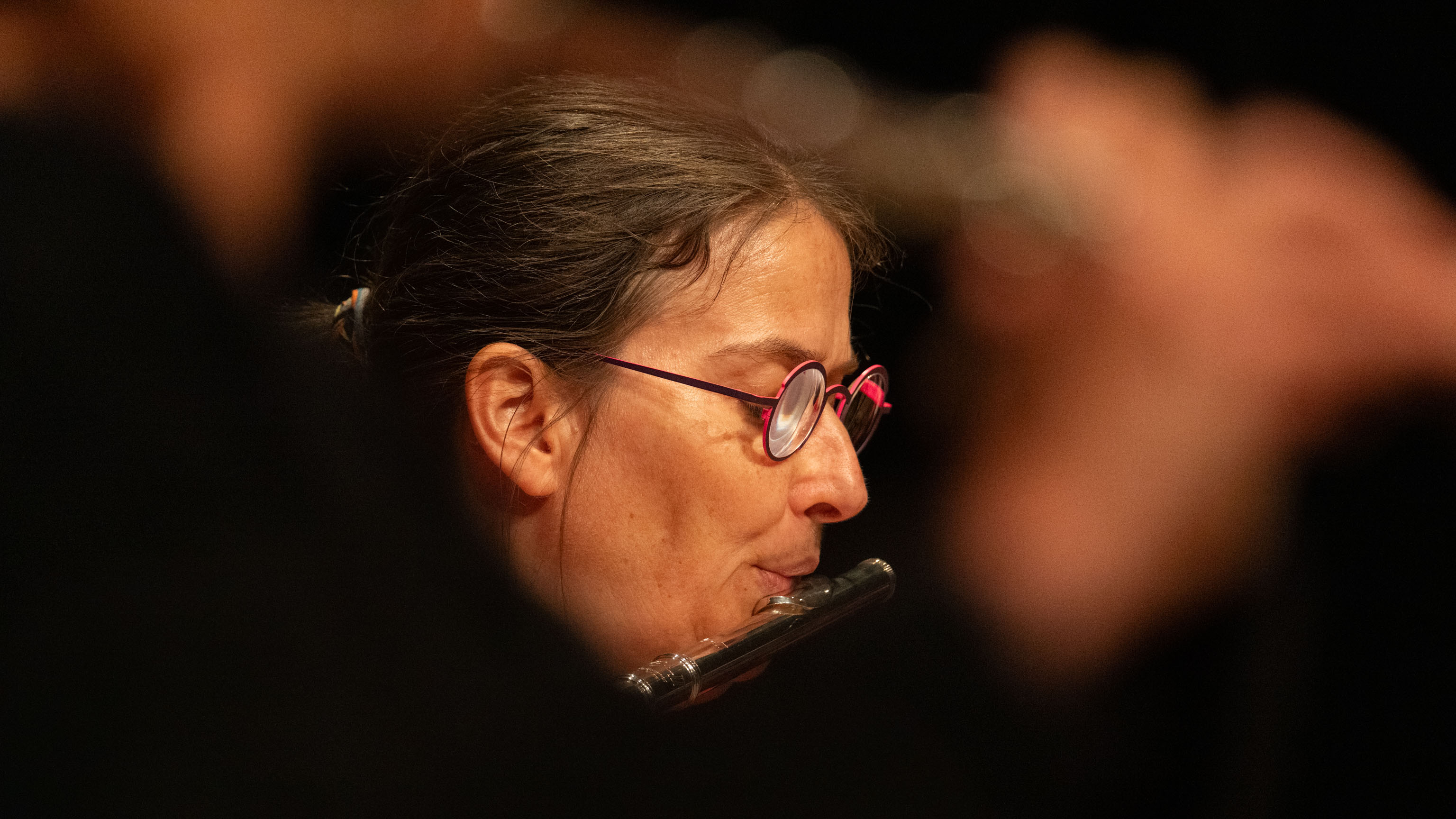 Maria beim Flötespielen in einer unscharfen Lücke zwischen ihren Mitspielerinnen