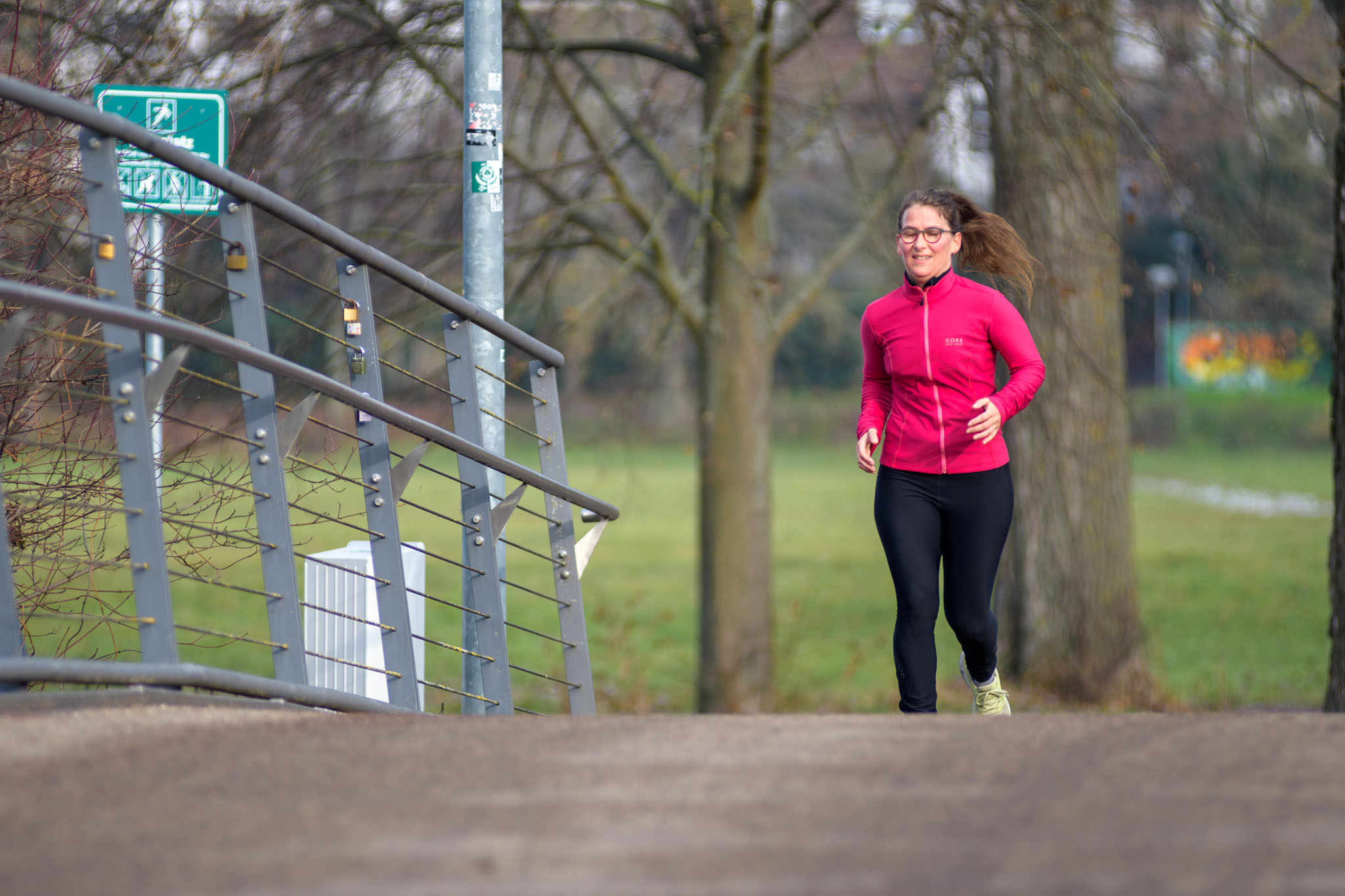 Mia kommt beim Joggen über eine Brücke im Stadtpark