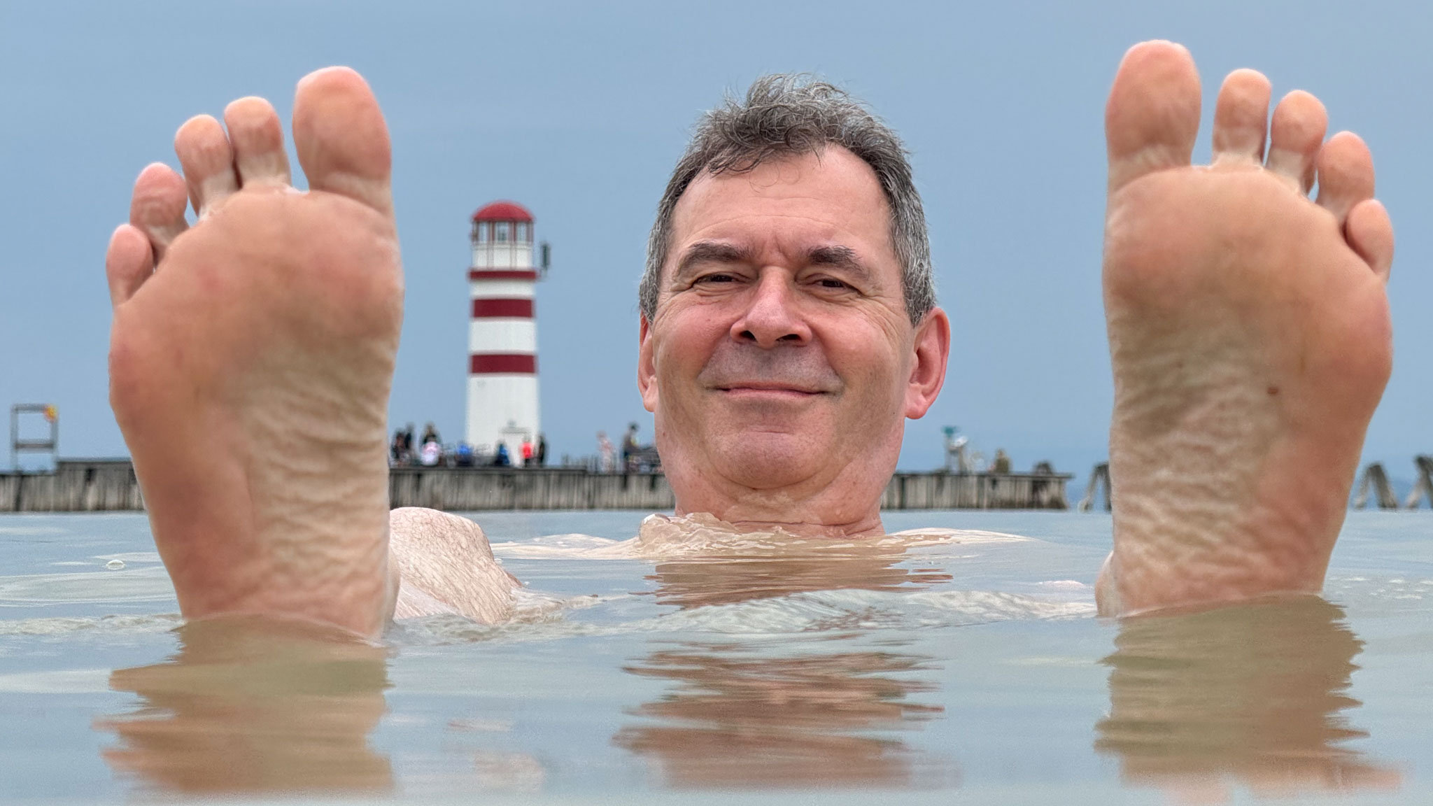 Thomas beim Baden im Neusiedler See – Füße aus dem Wasser – vor dem Podersdorfer Leuchtturm