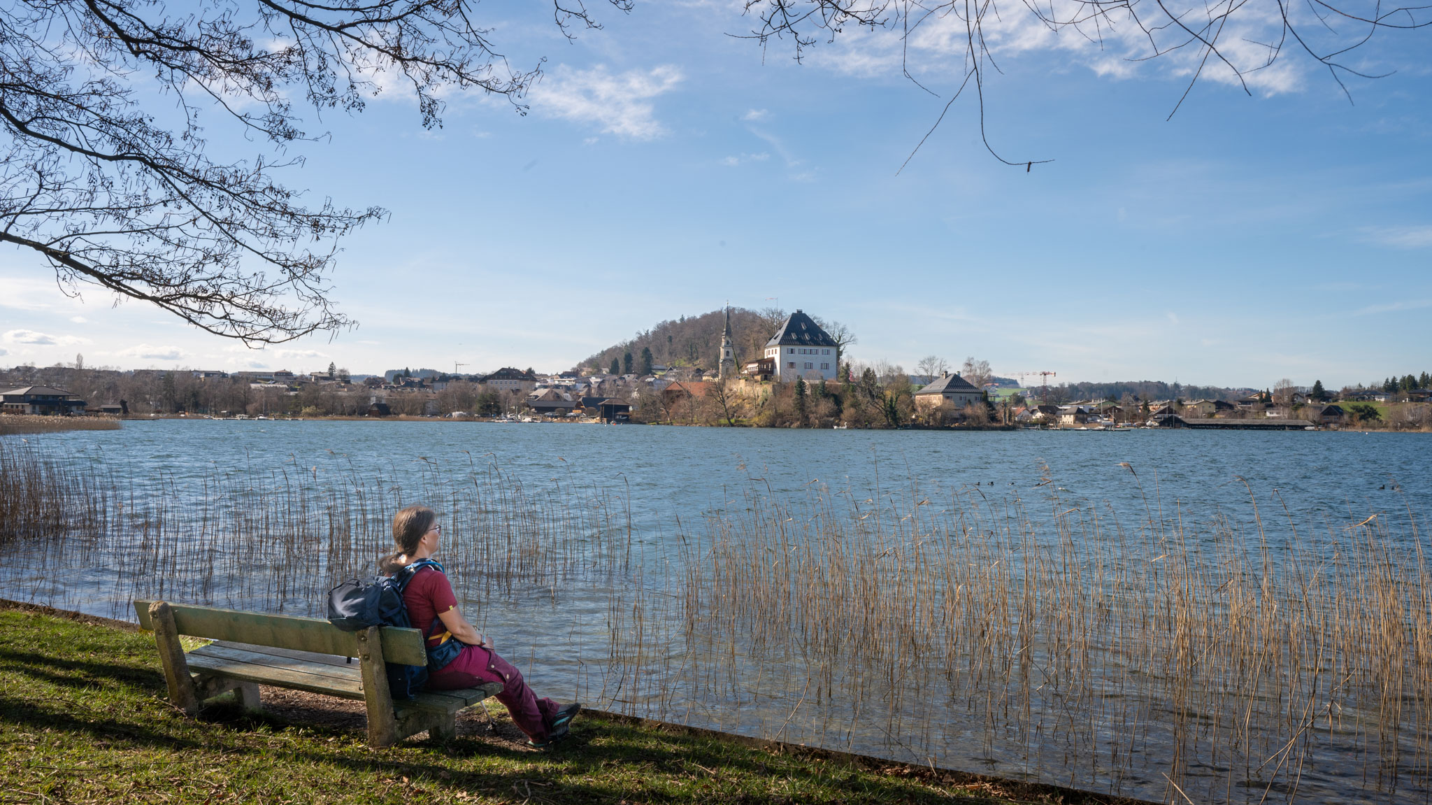 Maria auf Parkbank am Seeufer mit Blick auf das Schloss Mattsee